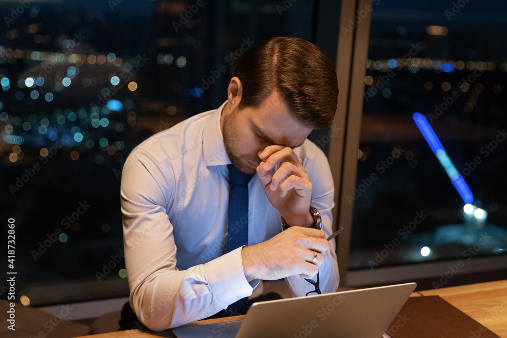Fototapeta premium Close up exhausted sleepy businessman using laptop, working at night, taking off glasses, suffering from eye strain, tired overworked employee executive finishing project, deadline concept