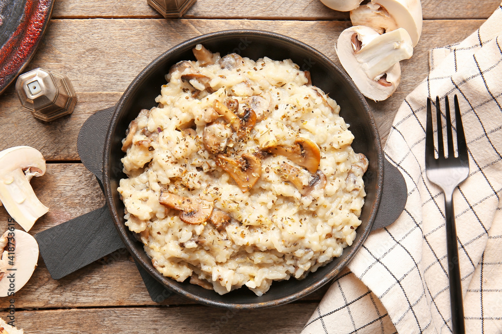 Frying pan with tasty risotto on wooden background Frying pan with tasty risotto on wooden background