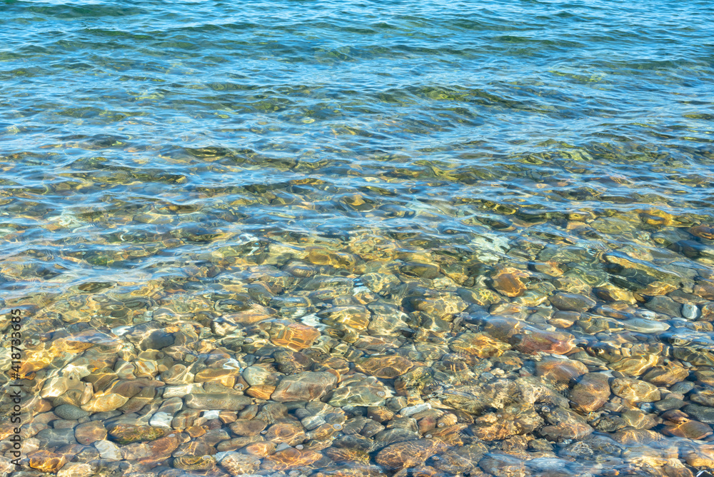 Clean water and stony bottom of the Baikal Lake at summer sunny day. Concept of relaxation, nature. Vocation time. Sea scene for card. Selective focus. Clean water and stony bottom of the Baikal Lake at summer sunny day. Concept of relaxation, nature. Vocation time. Sea scene for card. Selective focus.