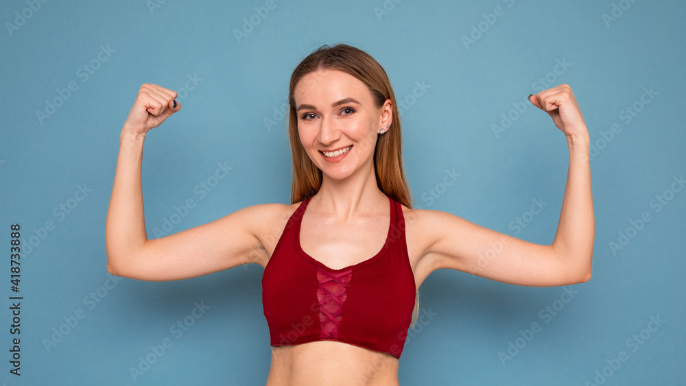 Young woman shows off her biceps on a blue background Young woman shows off her biceps on a blue background
