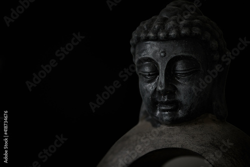 Buddha sculpture isolated on black background © Thomas Marx