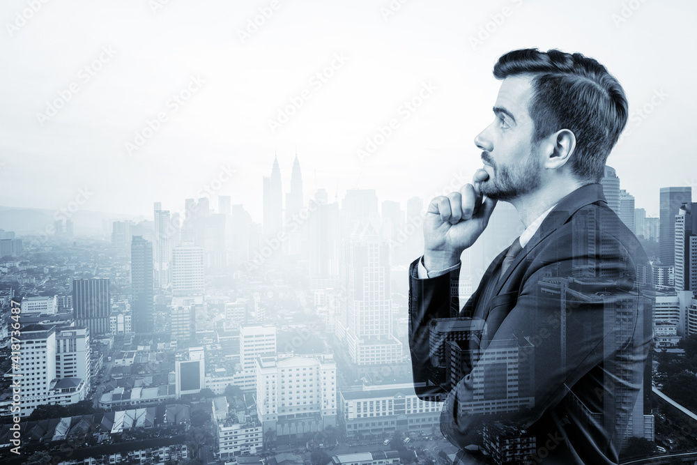 Young handsome businessman in suit with hand on chin thinking how to succeed, new career opportunities, MBA. Kuala Lumpur on background. Double exposure. Young handsome businessman in suit with hand on chin thinking how to succeed, new career opportunities, MBA. Kuala Lumpur on background. Double exposure.