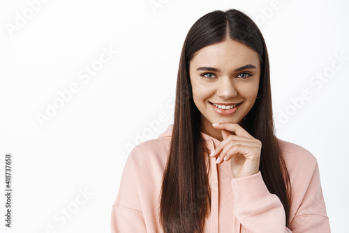 Close up of thoughtful beautiful woman with long healthy hair, looking determined and smiling, having an idea, good plan, white background