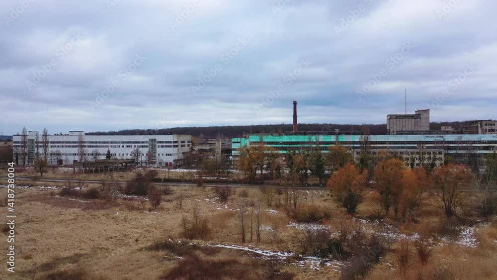 Old ruined factory among nature. Front view of a large ruined buildings of abandoned plant under gray sky. Old ruined factory among nature. Front view of a large ruined buildings of abandoned plant under gray sky.