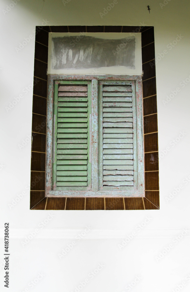 The old shutter window on white concrete wall.