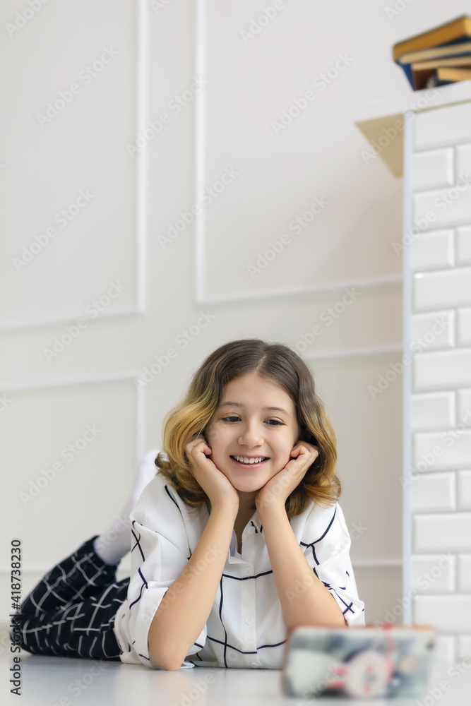 teenage girl smiling lying on the floor and watching online broadcast in smartphone teenage girl smiling lying on the floor and watching online broadcast in smartphone