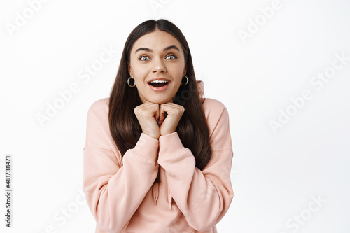 Portrait of excted young brunette girl open mouth wondered, leaning on hands while watching something awesome and beautiful, gasping fascinated, white background photo