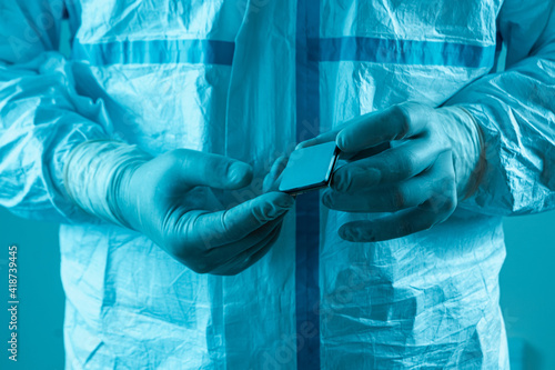 A man in sterile form holds a microprocessor, close-up. Microchip production technology, modern production, special microcircuit. Selective focus.