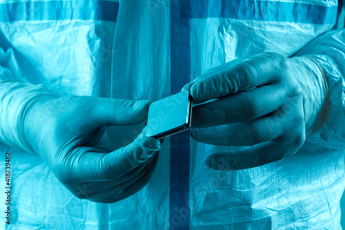 Microprocessor in hands in latex gloves in a sterile suit close-up. The concept of ultramodern microchip production, technology, modern plant, chip creation. Selective focus.