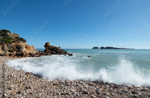 waves splashing onto a pebble beach in winter