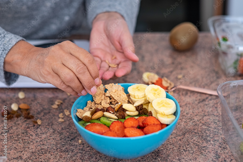 Female's hand preparing a bowl of fresh and dried fruits. Breakfast or lunch time, healthy eating Female's hand preparing a bowl of fresh and dried fruits. Breakfast or lunch time, healthy eating