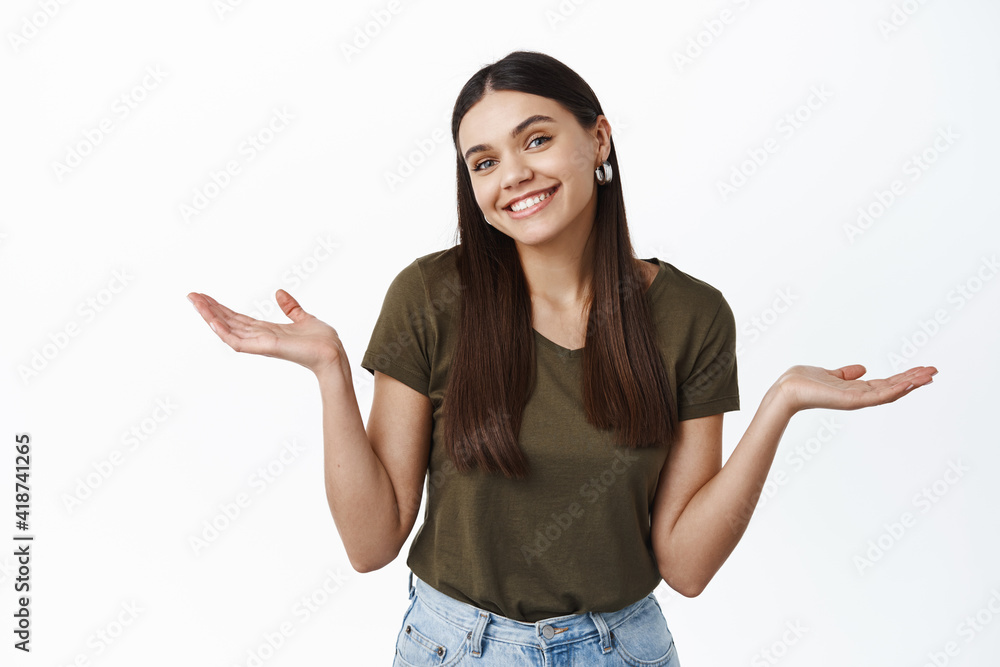 Oops. Cute smiling young woman shrugging with empty hands spread sideways, know nothing, cant help you sorry, standing over white background Oops. Cute smiling young woman shrugging with empty hands spread sideways, know nothing, cant help you sorry, standing over white background