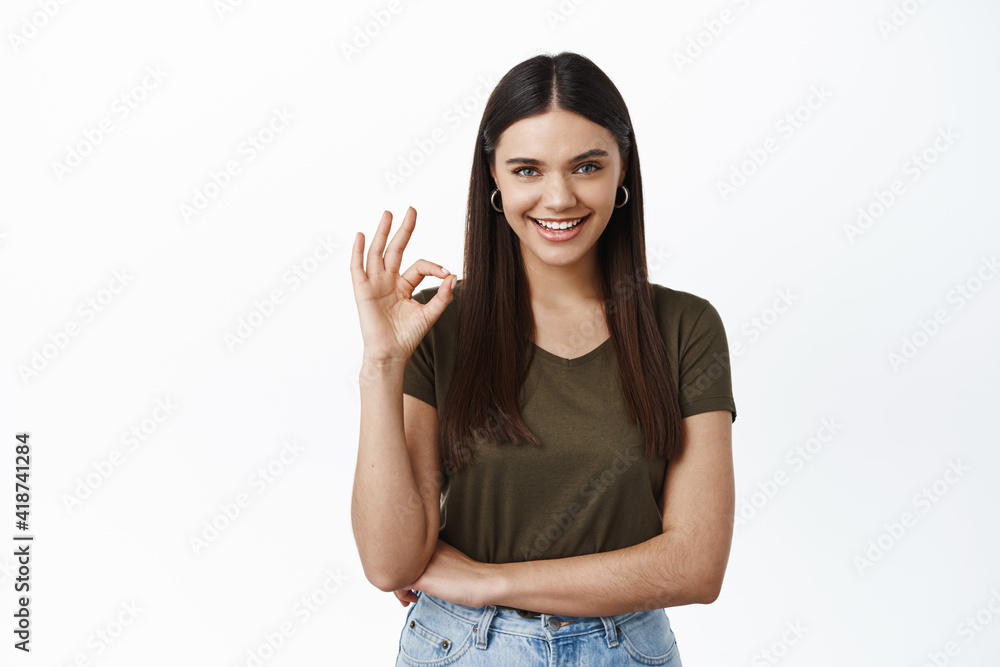 Alright that a deal. Confident smiling woman say yes, showing okay sign in approval, praise good choice, standing satisfied against white background Alright that a deal. Confident smiling woman say yes, showing okay sign in approval, praise good choice, standing satisfied against white background