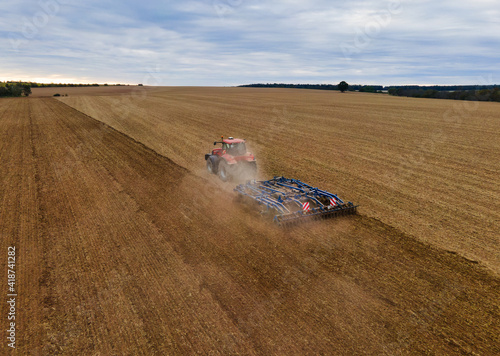 Принти на полотні Farmer with tractor on wide field tilling the soil