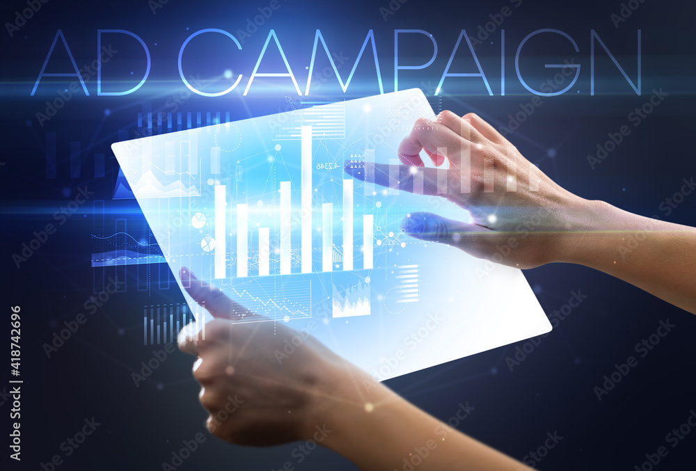 Hand holding futuristic tablet with AD CAMPAIGN inscription above, modern business concept Hand holding futuristic tablet with AD CAMPAIGN inscription above, modern business concept