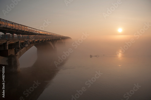Sunrise over the spring river. A bridge over a large river.. Fog on the river in early spring