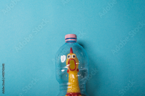 Yellow chicken in a plastic bottle on a blue background.Concept of stop plastic pollution,global warming,recycling plastic,plastic free.