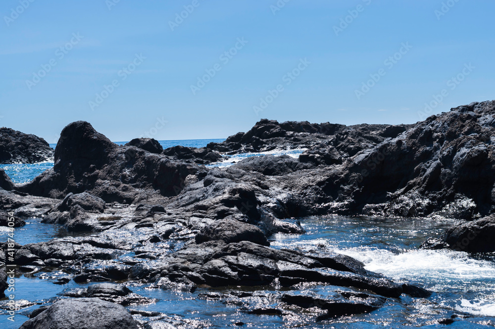 Vulkanische Küstenlandschaft, mit aufgewühltem Meer, welches in der Mittagssonne glitzert