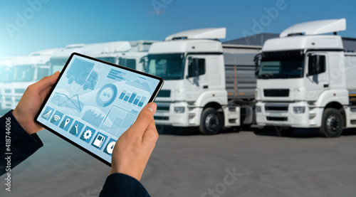 Fotografie Manager with a digital tablet on the background of trucks