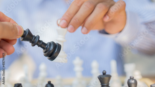 A business man playing a black and white chess game on the board The concept of business strategy for the brain.