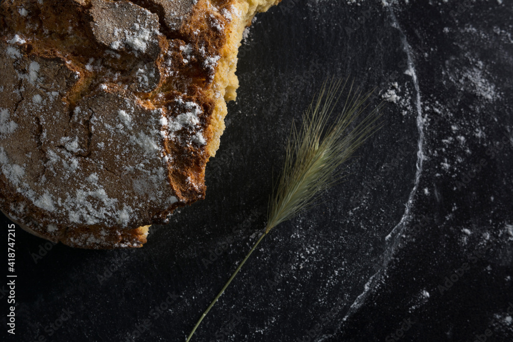 Pan de maíz abierto sobre pizarra negra con espiga Pan de maíz abierto sobre pizarra negra con espiga
