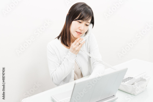 Woman talking on a landline while operating a PC