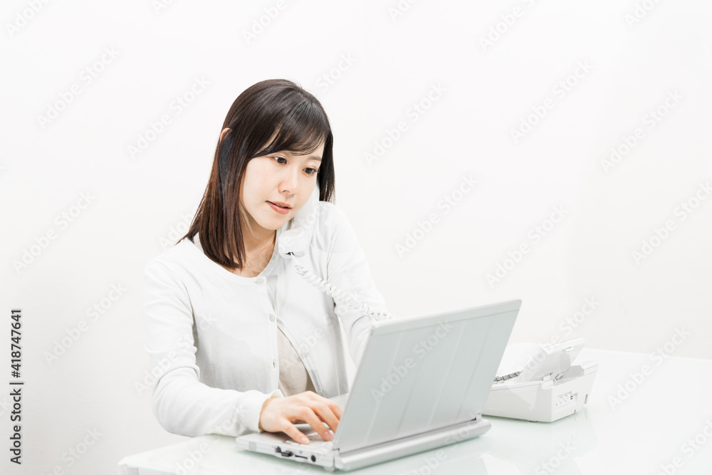 Woman talking on a landline while operating a PC Woman talking on a landline while operating a PC