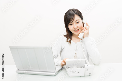 Woman talking on a landline while operating a PC