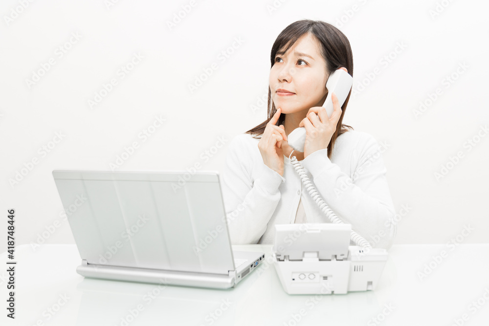 Woman talking on a landline while operating a PC Woman talking on a landline while operating a PC