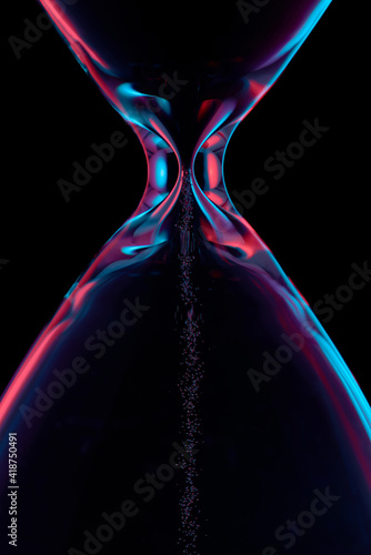Hourglass illuminated in red and blue on a black background