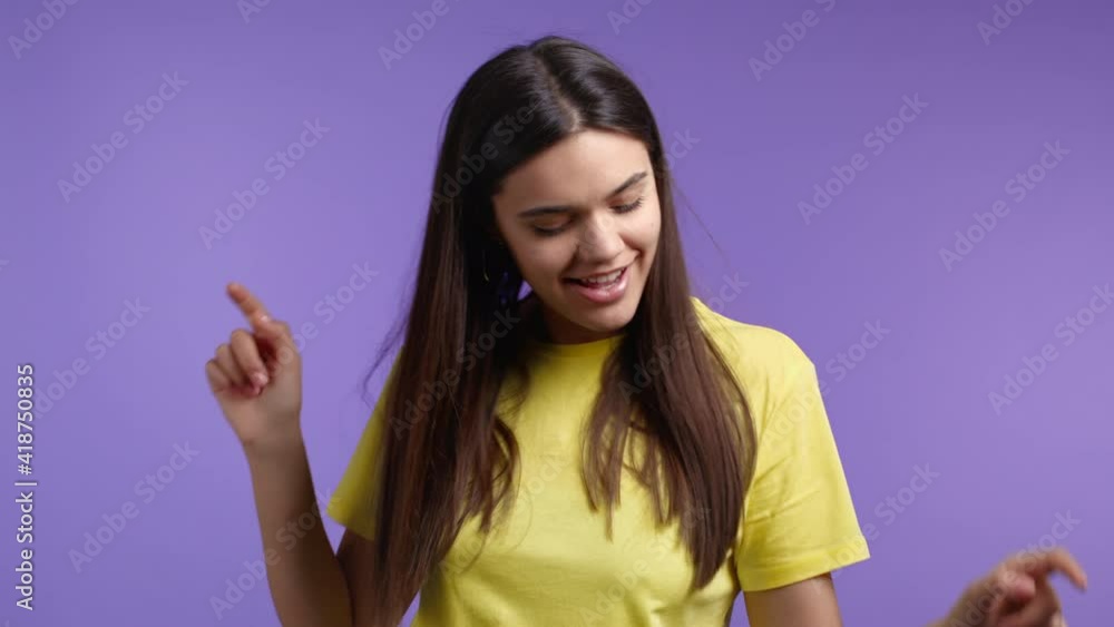 Woman dancing positive on violet studio background. Pretty female model in yellow t-shirt. Party, happiness, freedom, youth concept. Woman dancing positive on violet studio background. Pretty female model in yellow t-shirt. Party, happiness, freedom, youth concept.