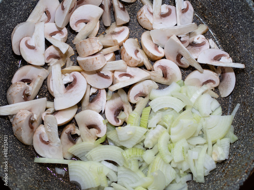 cut raw mushrooms in a frying pan with . cooking dinner.