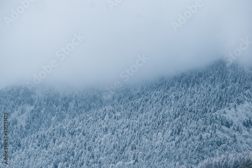 Snowy mountain covered in clouds in winter © Matej
