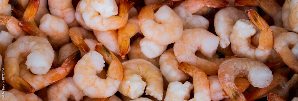 Close-up of a pile of frozen orange shrimps. Peeled shrimp, leaving only tails. Natural seafood background Close-up of a pile of frozen orange shrimps. Peeled shrimp, leaving only tails. Natural seafood background