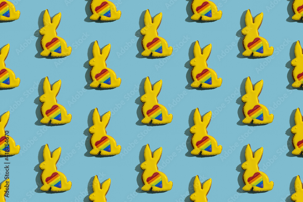 Food pattern. Seamless banner. Lgbtqia equality. Gay pride symbol. Conceptual art. Bunny gingerbread cookies with yellow icing rainbow heart ornament isolated on blue textured. Food pattern. Seamless banner. Lgbtqia equality. Gay pride symbol. Conceptual art. Bunny gingerbread cookies with yellow icing rainbow heart ornament isolated on blue textured.