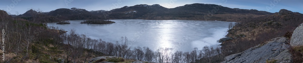 Fototapeta premium Hiker with Samoyed husky dog looking at frozen lake and fjord in Rogaland Norway