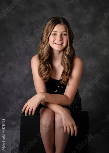 Фотография Beautiful confident tween girl with long hair in a black sparkly dress