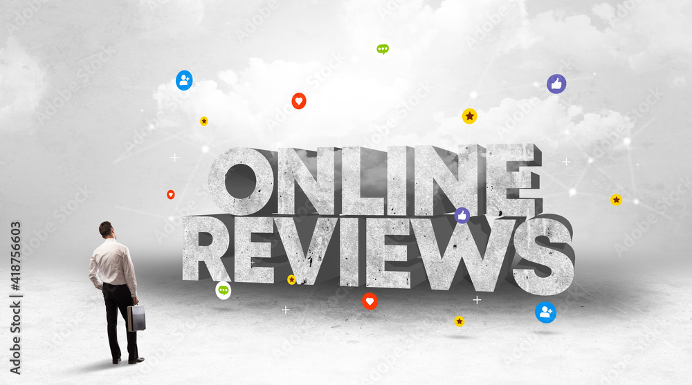 Young businessman standing in front of ONLINE REVIEWS inscription, social media concept Young businessman standing in front of ONLINE REVIEWS inscription, social media concept