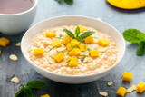 Rice pudding with cinnamon and mango in white bowl