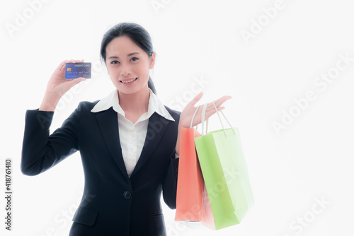 Asian female company employee in a black suit Hold paper bags for goods After shopping for products using credit cards happily on isolate white background