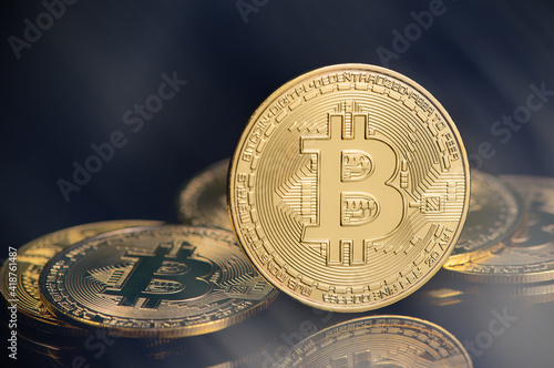 Bitcoin e-cryptocurrency on black background with rays. Golden virtual currency coin. High quality photo