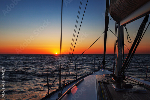 Sailing boat at open sea at colorful sunset