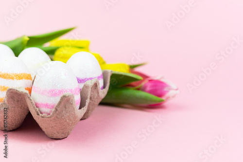 Easter painted eggs with tulips on a pink background. Copy space. Easter celebration concept