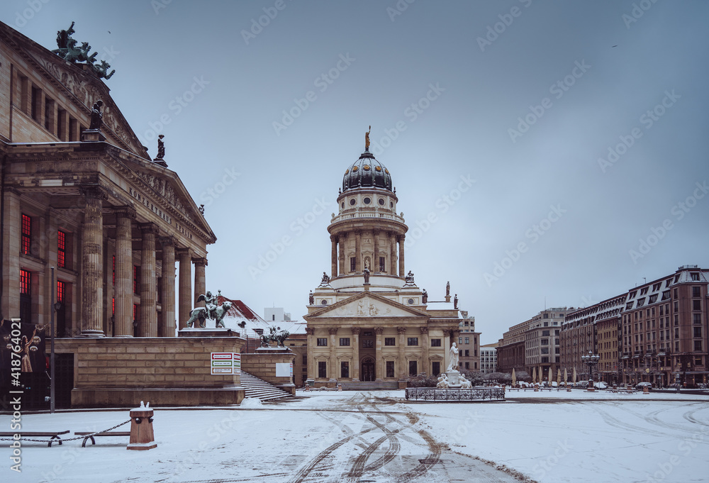 Snow and winter panoramic view of famous Gendarmenmarkt square with Berlin Concert Hall and German Cathedral. Early morning light with clouds after blizzard in winter, Berlin Mitte district, Germany