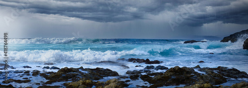 Ocean coast with dark rain thunder storm, stormy clouds and high waves sea. Dramatic seascape background.