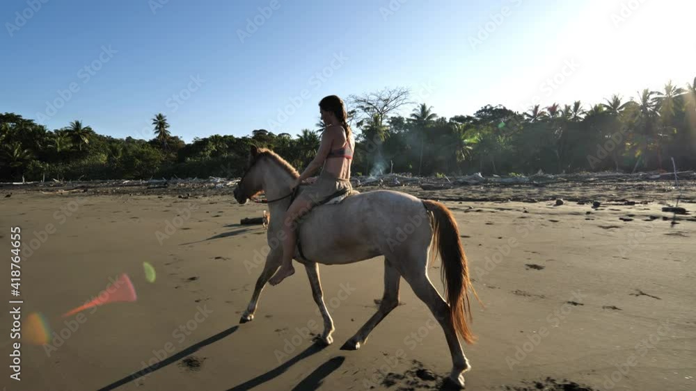 Woman on a horse on a beach with jungle sunrise Costa Rica galloping horse motion Woman on a horse on a beach with jungle sunrise Costa Rica galloping horse motion