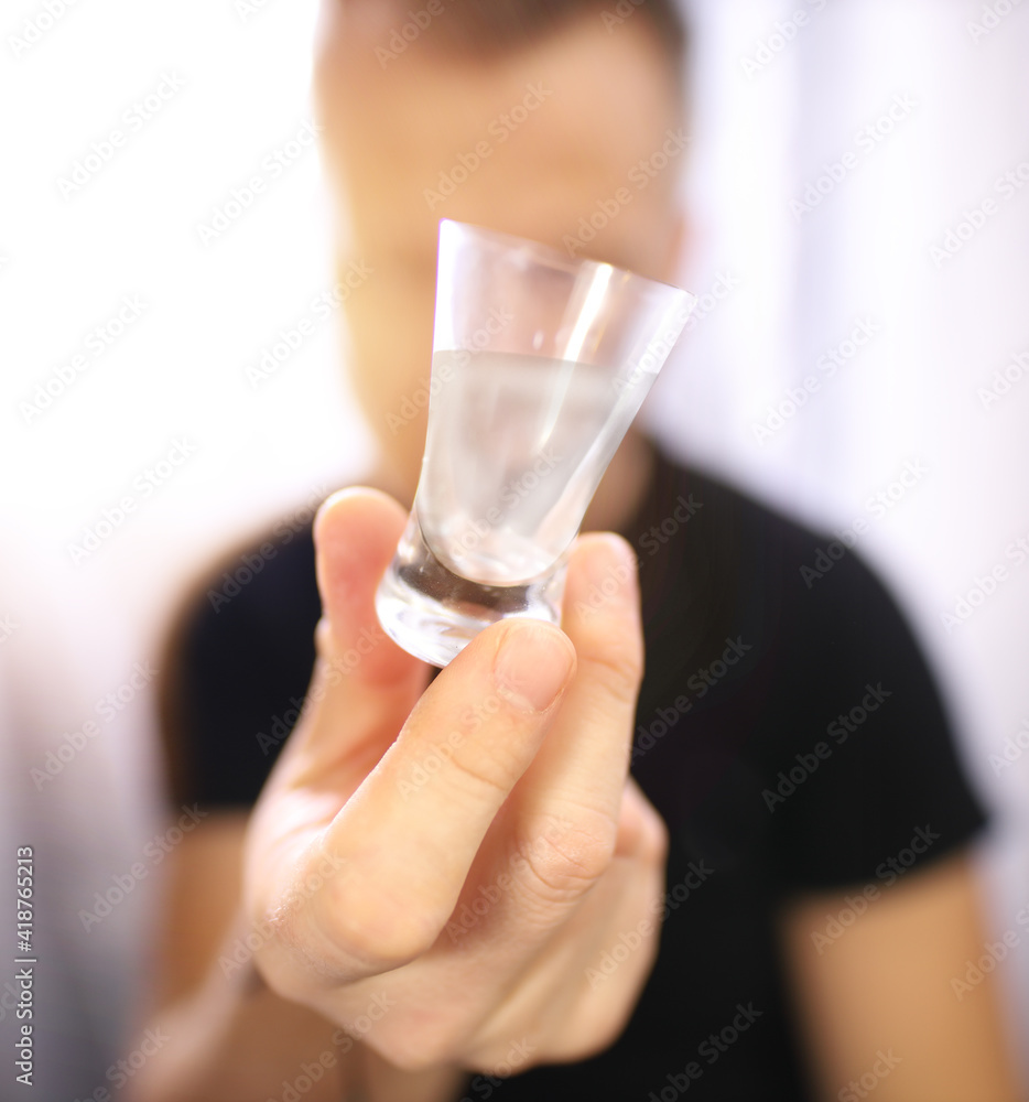 © ambrozinio - man with an alcohol problem holds a glass in his hand