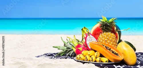 Fototapeta Naklejka Na Ścianę i Meble -  Panorama of fresh different tropical fruits placed on the beach with blue sky and sea background.