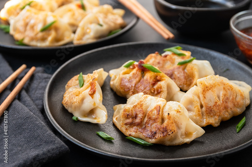 Delicious gyoza dumplings fried on a on black plates  with soy sauce