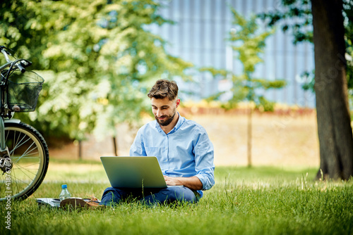 Young business man working on laptop in park